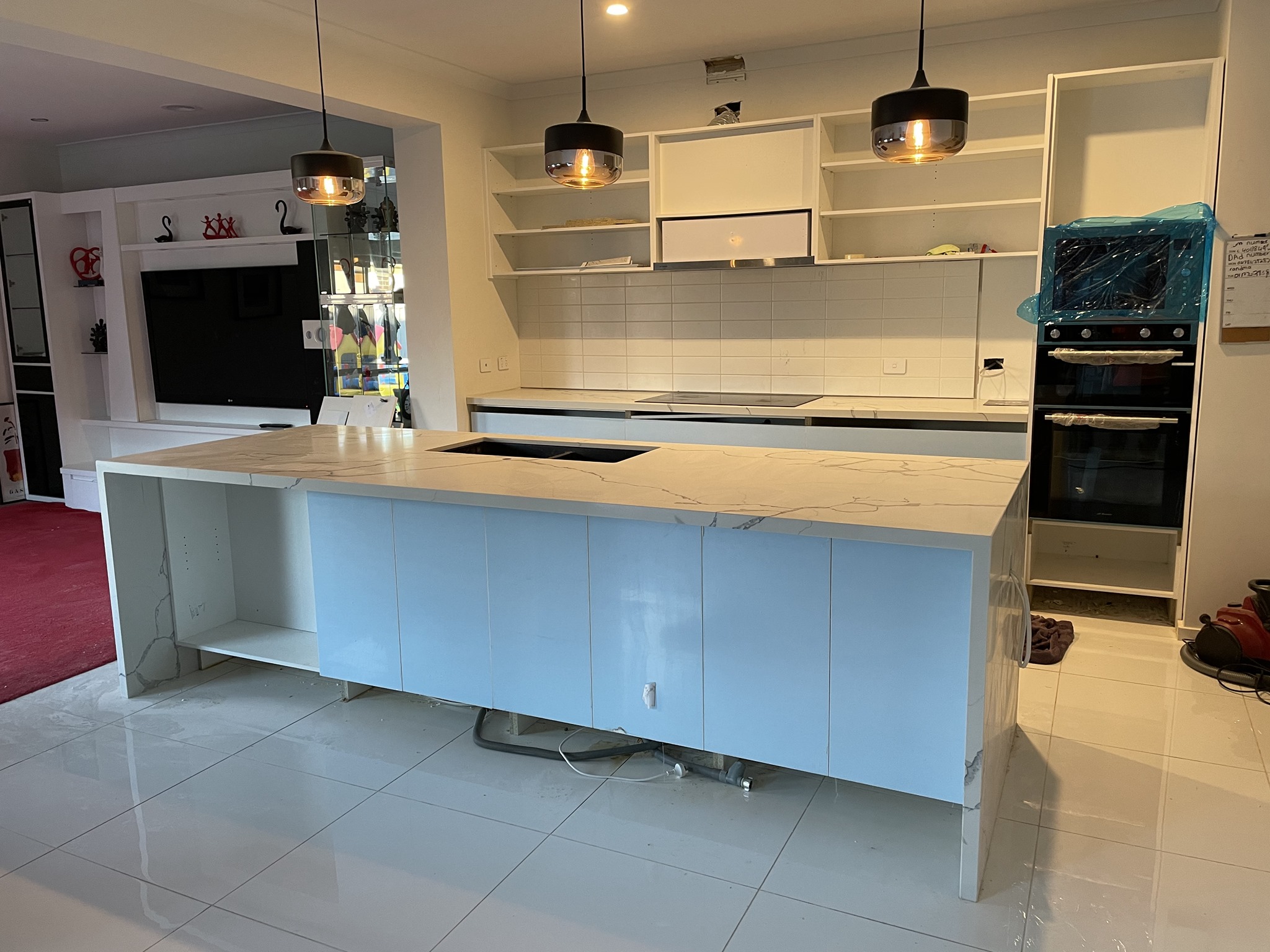Wide view of a kitchen island with a white marble-look top and pendant lights