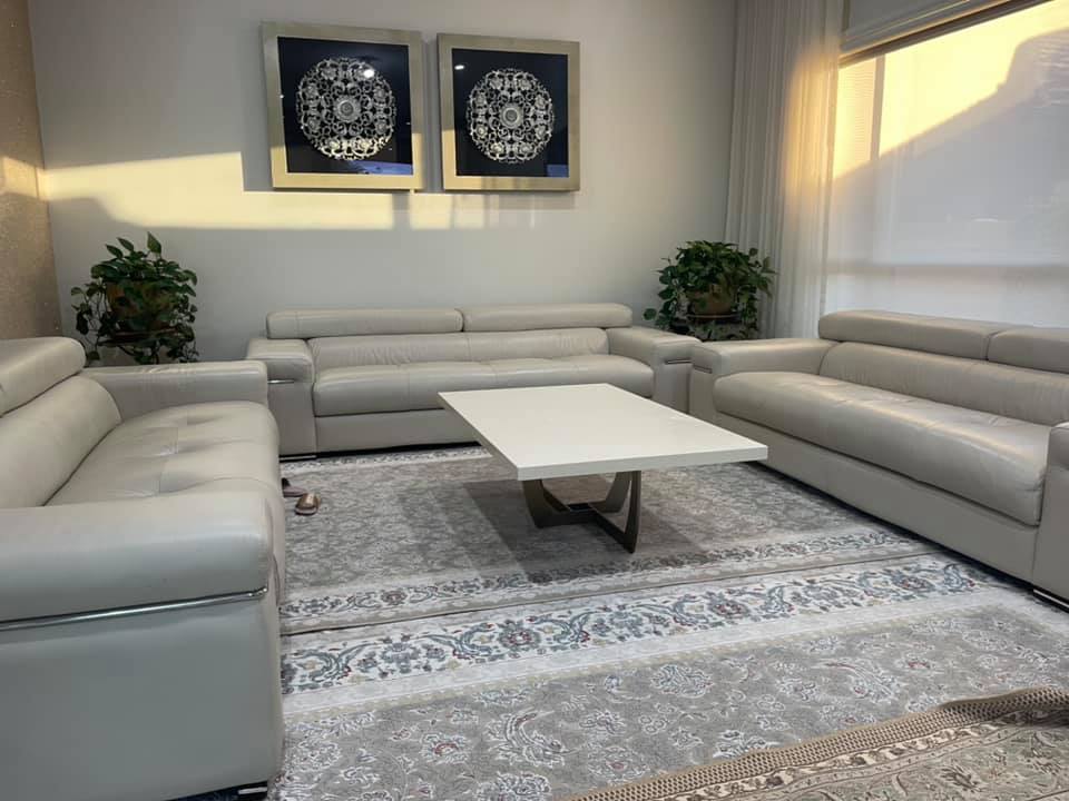 White stone coffee table between grey leather sofas