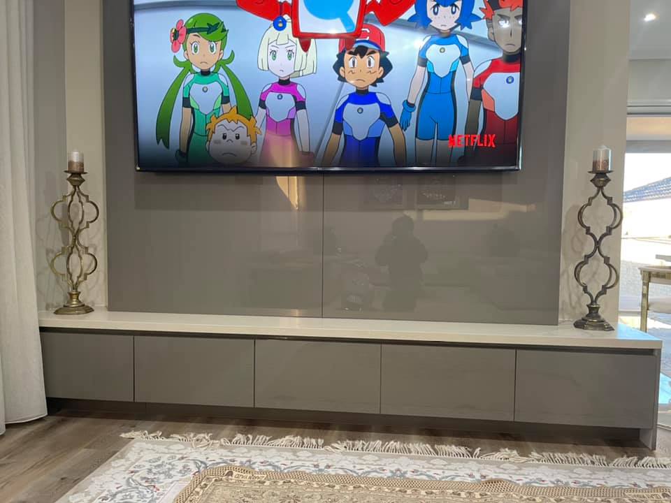 Grey TV cabinet with a pale stone top under a wall-mounted TV