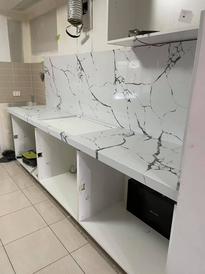 Portrait view of a white benchtop with bold dark veining over open cabinets