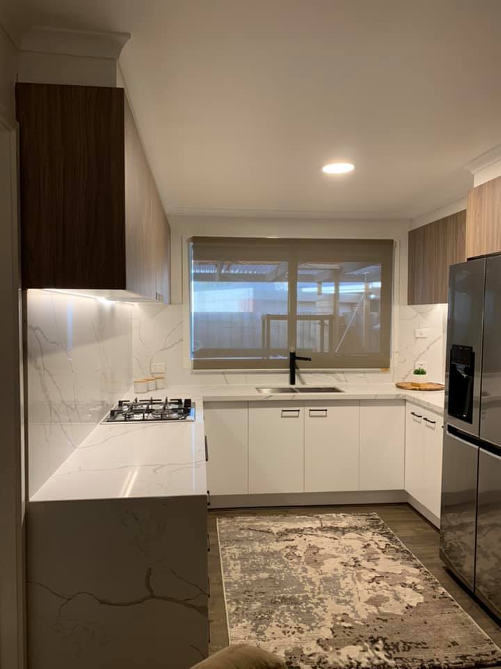 Galley kitchen with white veined stone benchtops and splashbacks