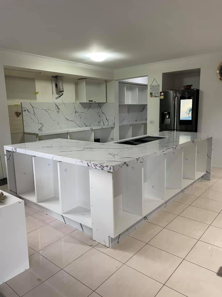 Large white veined benchtop over open cabinets in an unfinished kitchen