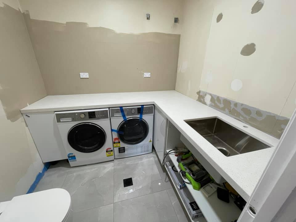 Laundry with a white stone benchtop, undermount sink and two washing machines