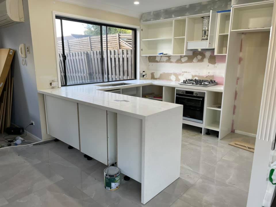 Kitchen with a white stone peninsula benchtop and waterfall end
