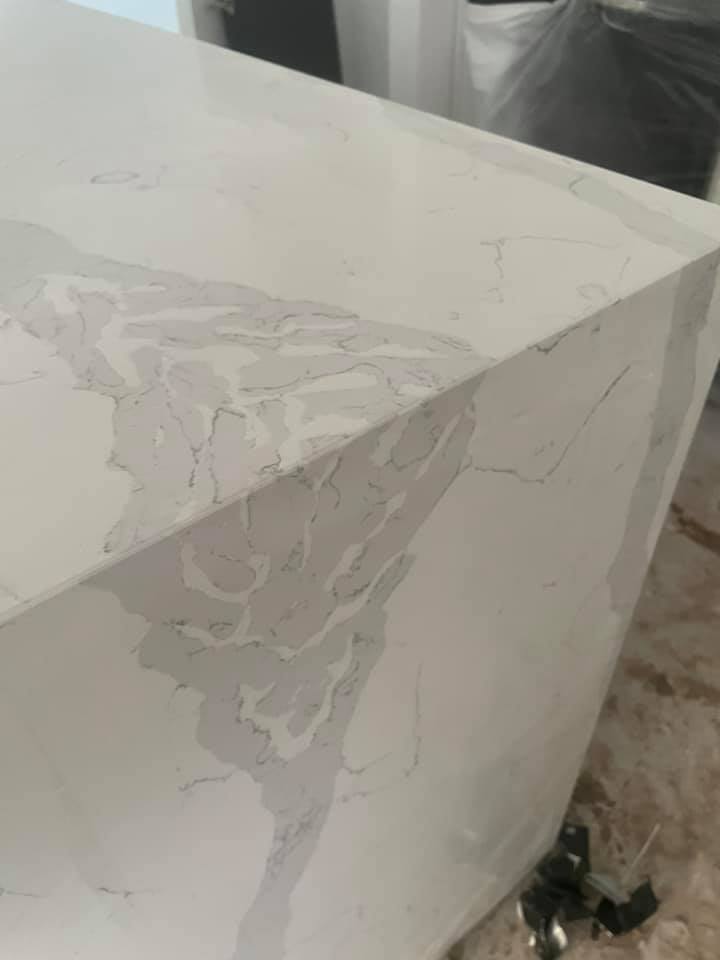 Close-up of a mitred waterfall edge on a white veined stone benchtop