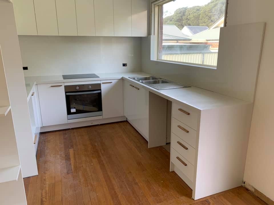 U-shaped white kitchen with stone benchtops, double sink and timber floor