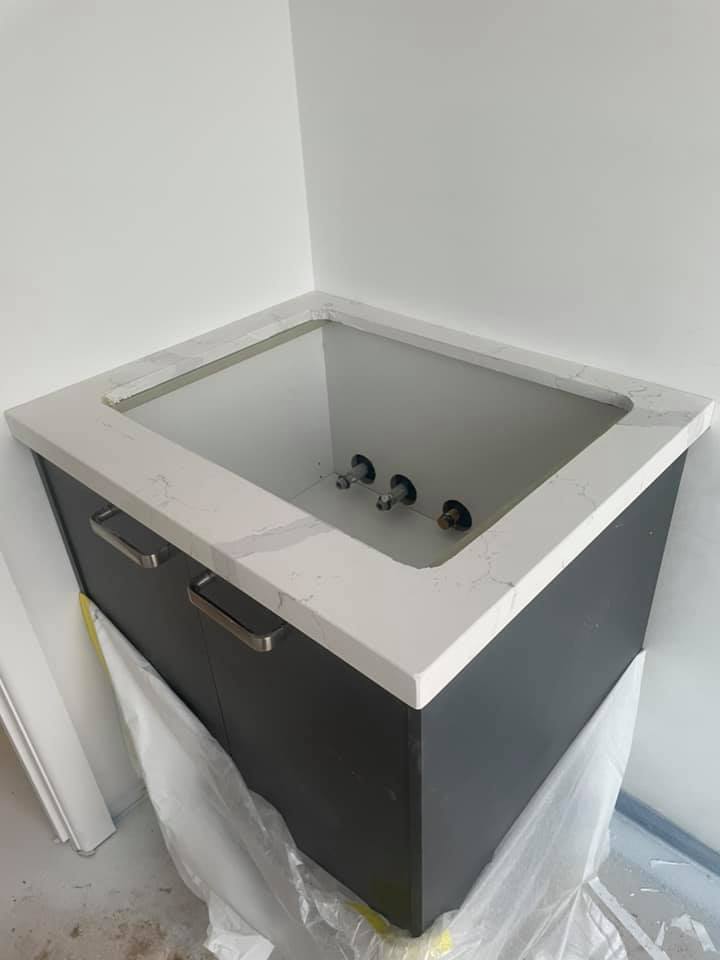 White stone top with a square sink cut-out on a dark cabinet