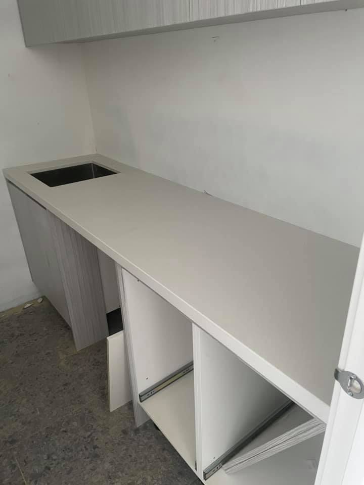 Long white stone benchtop with a sink cut-out over unfinished cabinets