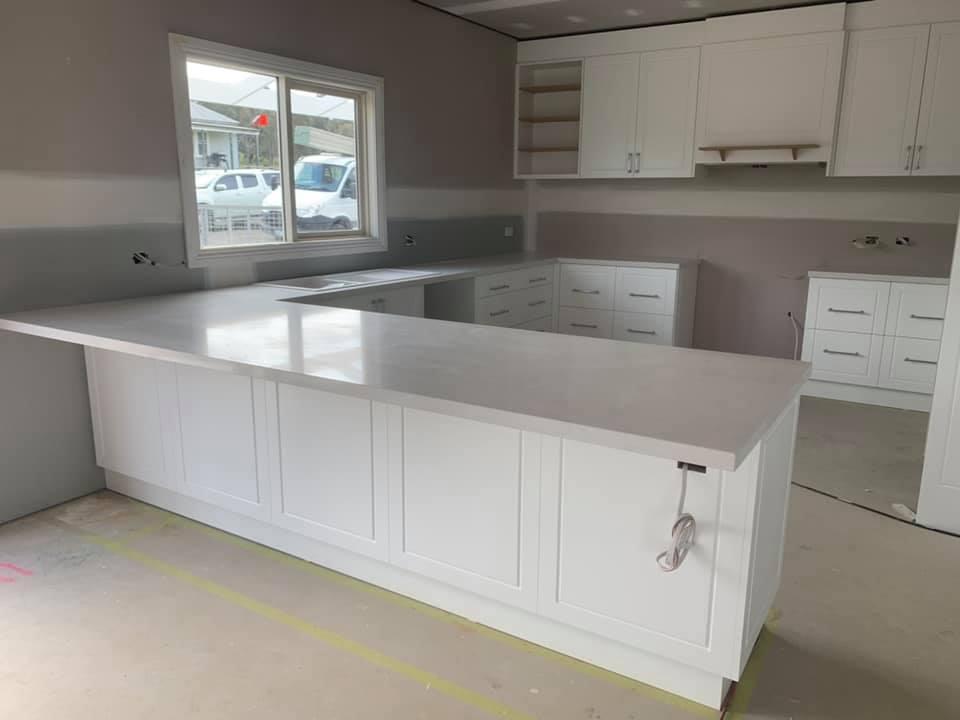 Large L-shaped white stone benchtop on white shaker-style cabinets