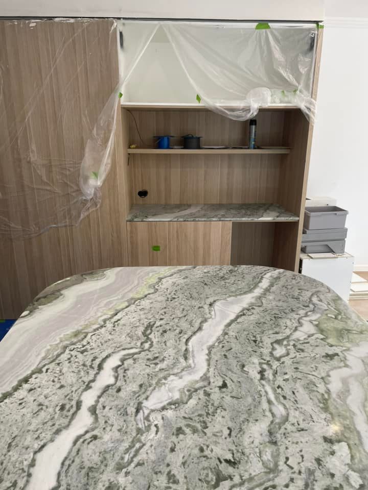 Green and white veined stone benchtop with timber cabinetry behind