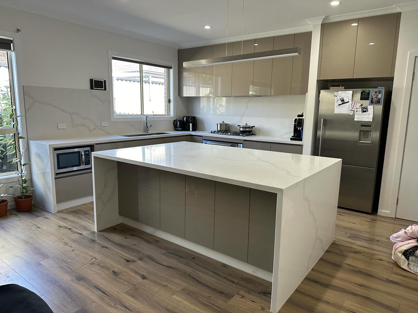 Wider view of a white veined stone waterfall island on a timber floor