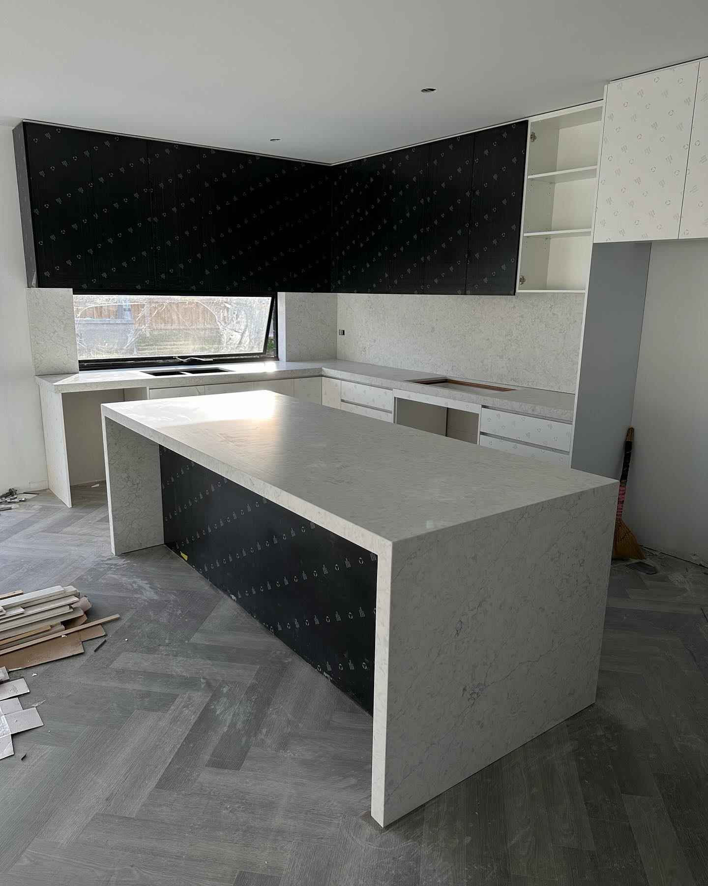 White stone island with waterfall ends and a black front panel, herringbone floor