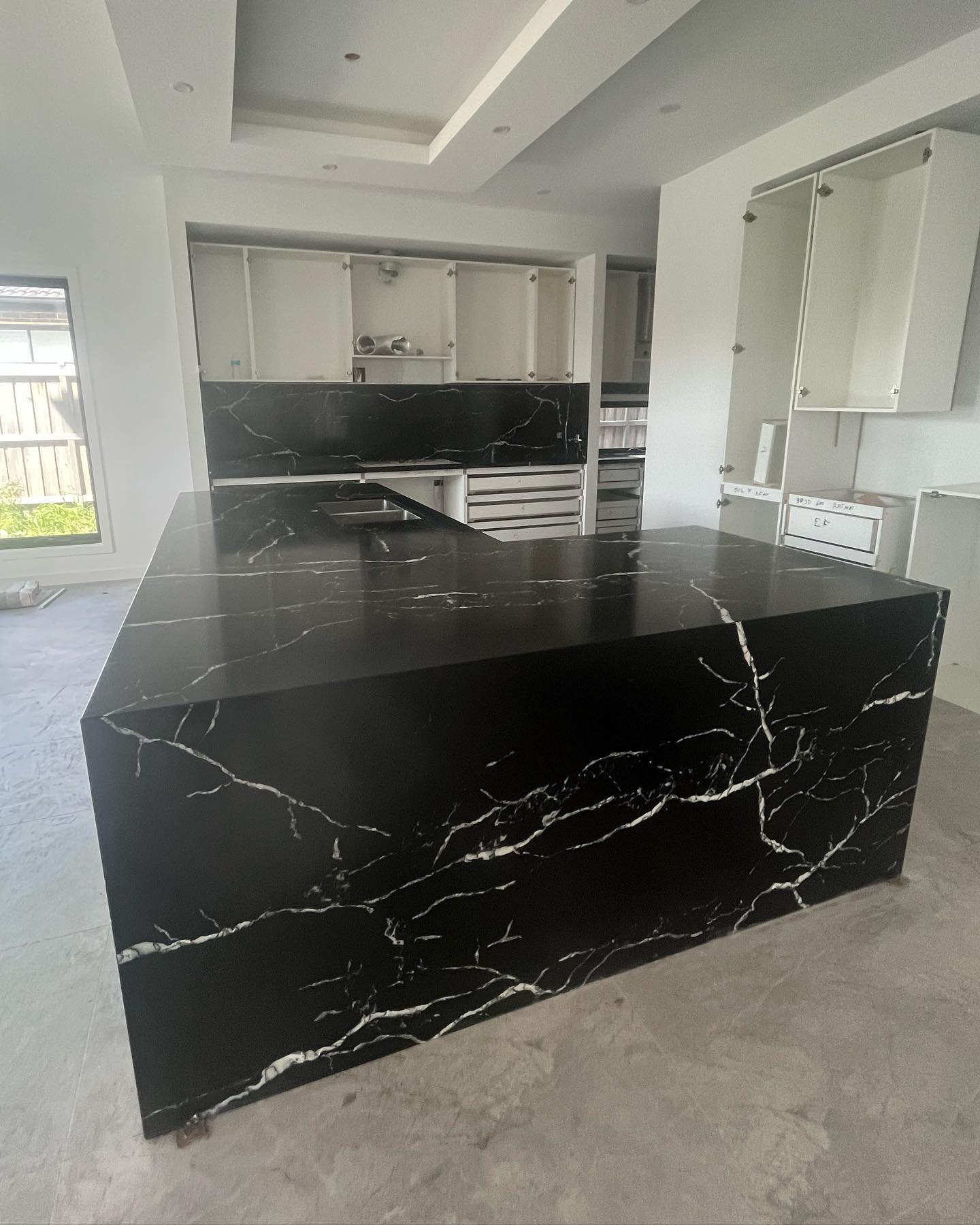 Corner view of a black marble-look waterfall island with white veining
