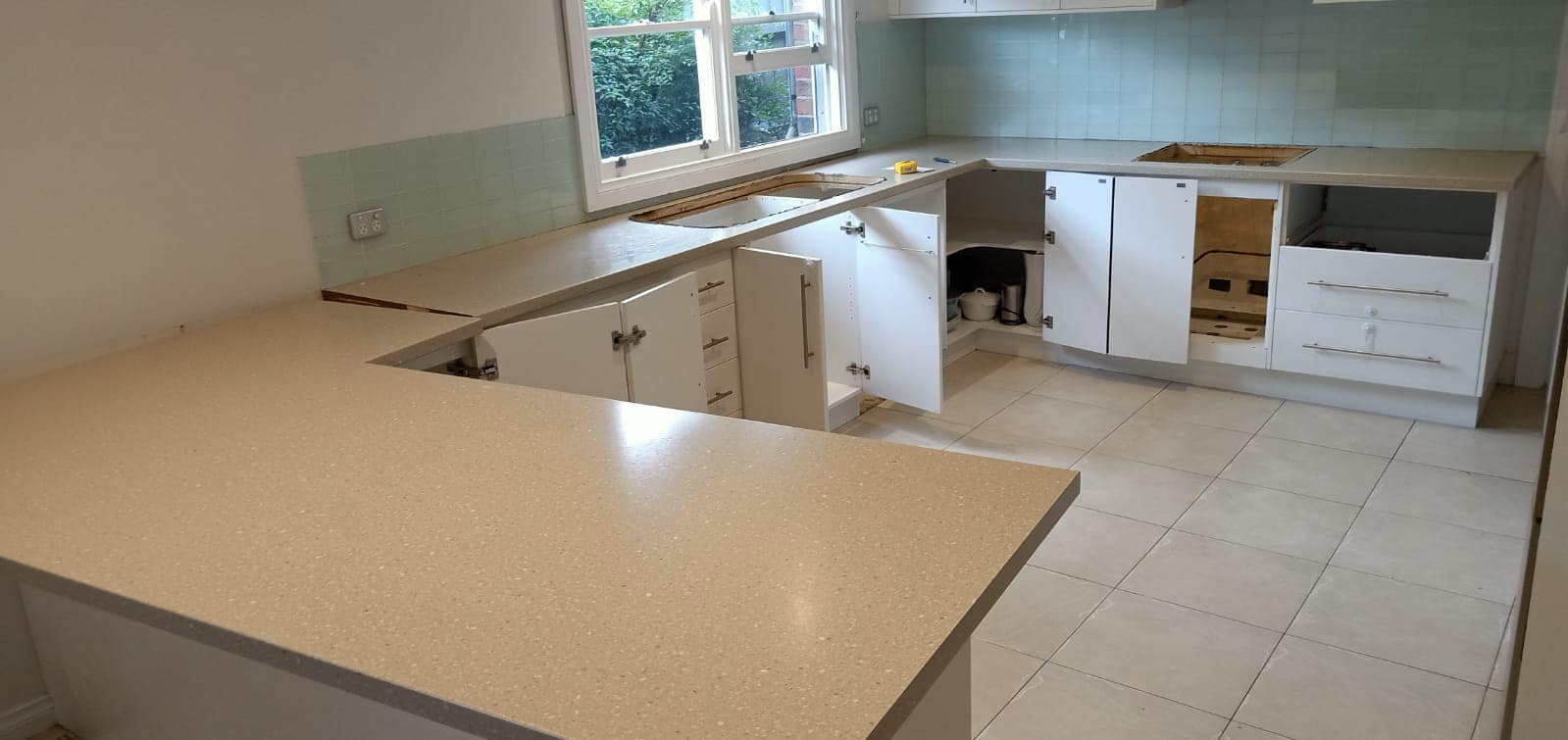 L-shaped kitchen with a beige speckled stone benchtop