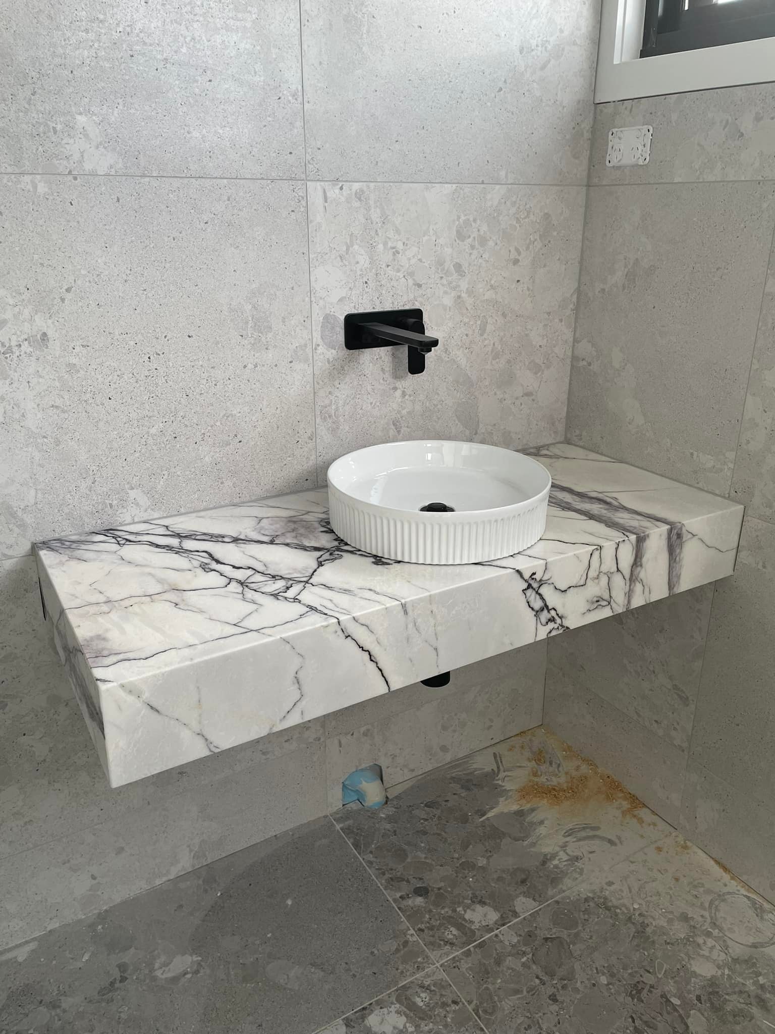 Angled view of a floating purple-veined marble vanity with a round basin