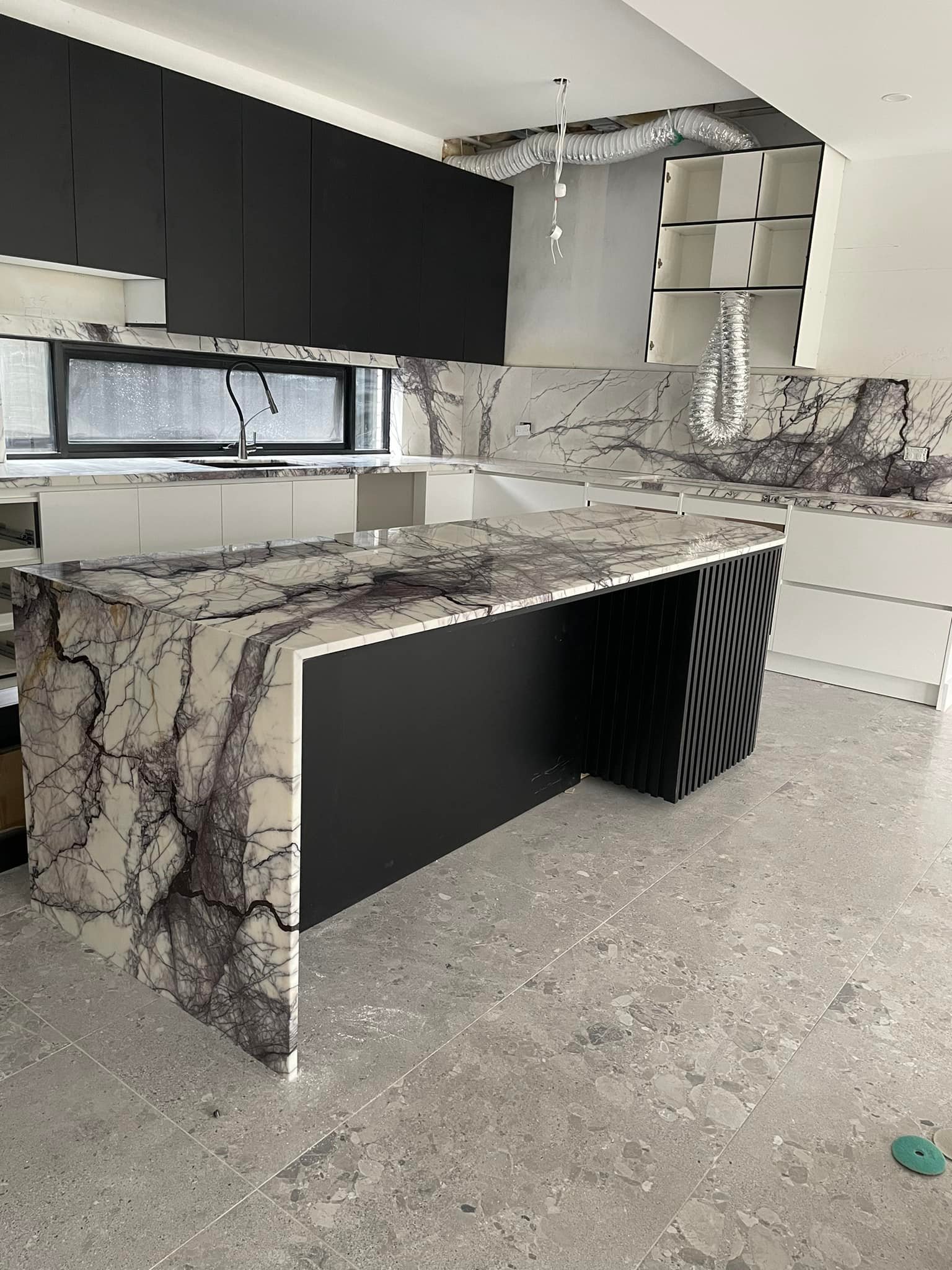 Purple-veined marble island and splashback seen from the far end