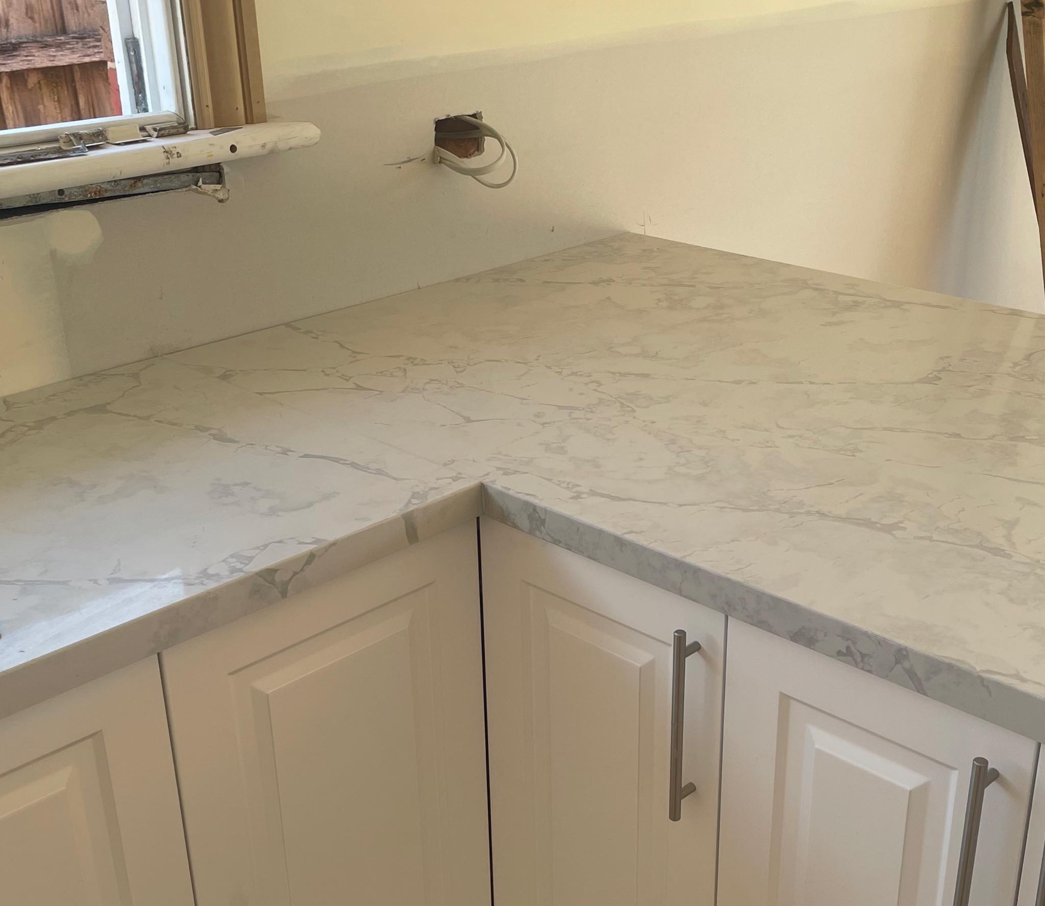 L-shaped pale grey marble-look benchtop on white cabinets