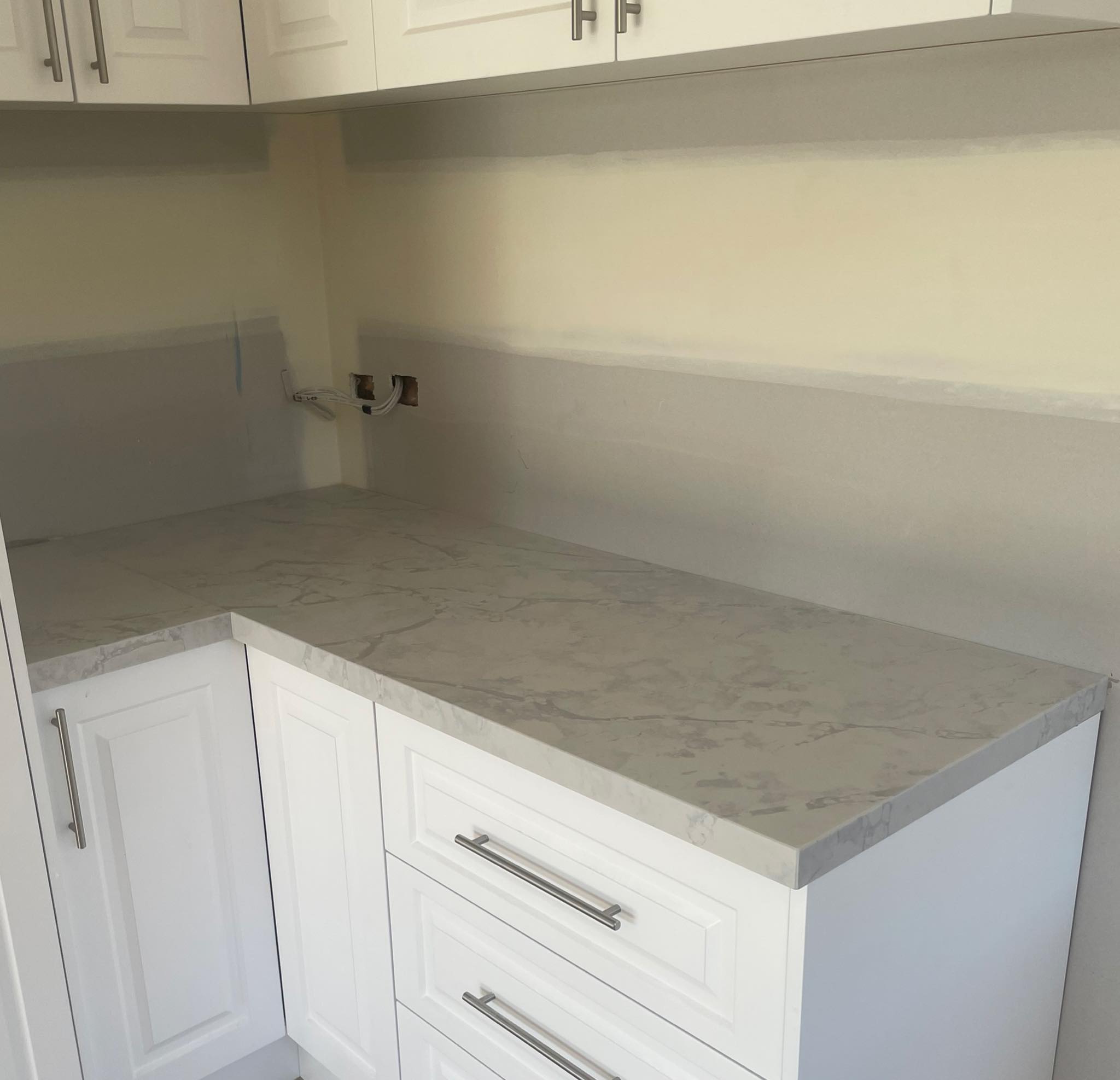 Corner of a grey veined stone benchtop above white drawers