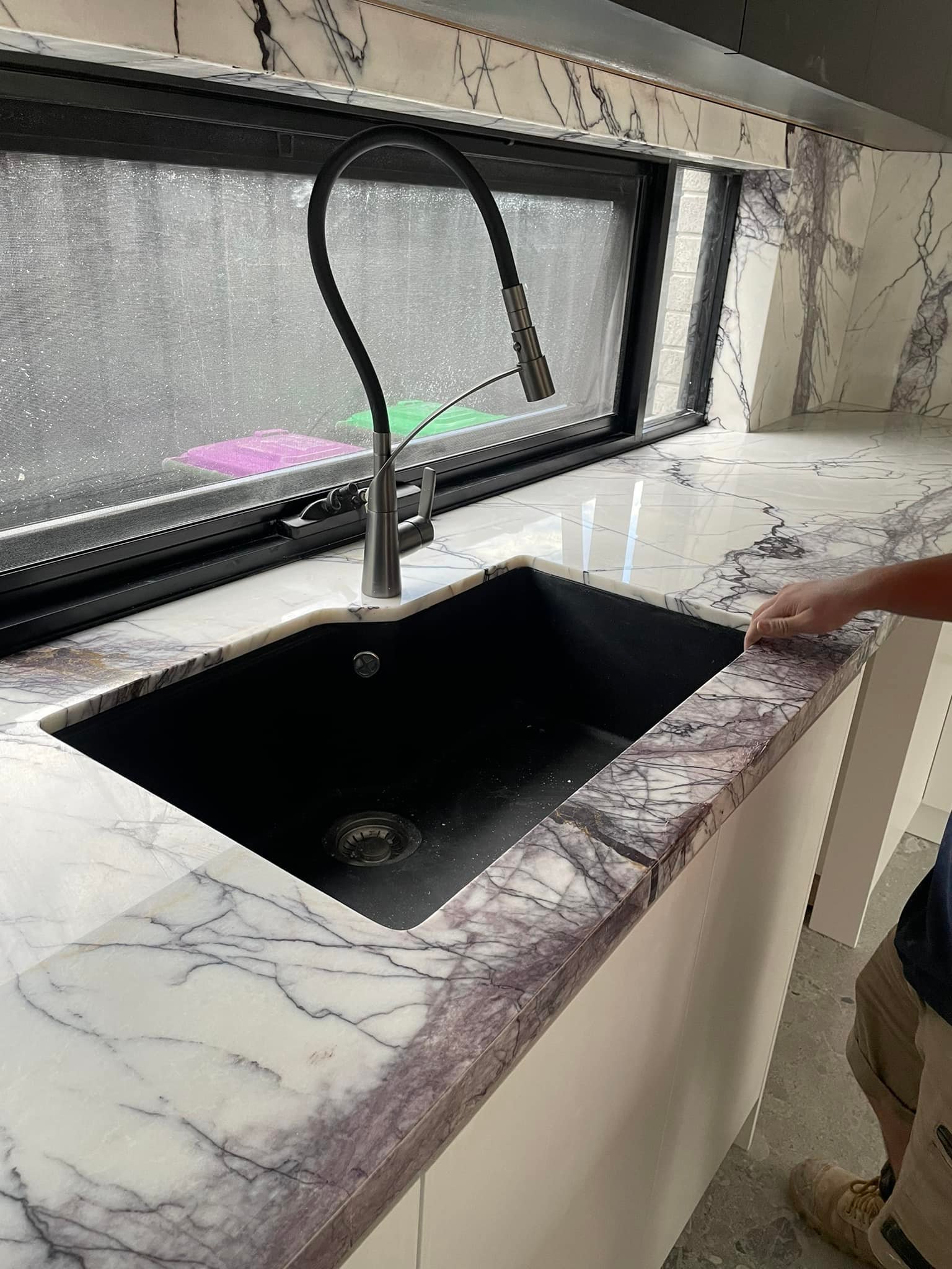 Close-up of a purple-veined marble benchtop with a black sink and pull-out tap