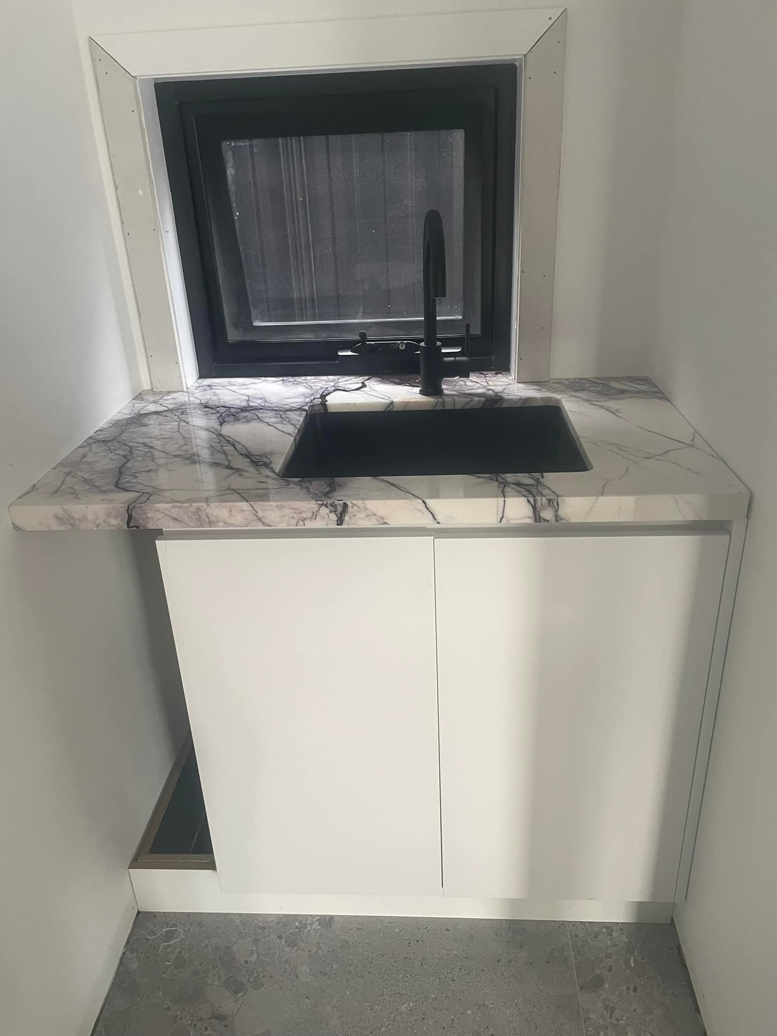 Small purple-veined marble benchtop with a black sink under a window