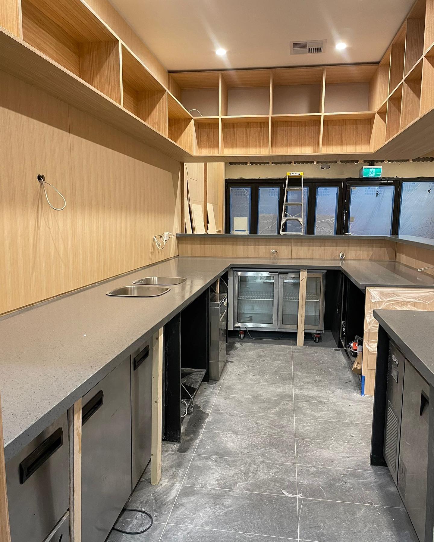 Commercial kitchen with long grey stone benchtops along timber-lined walls