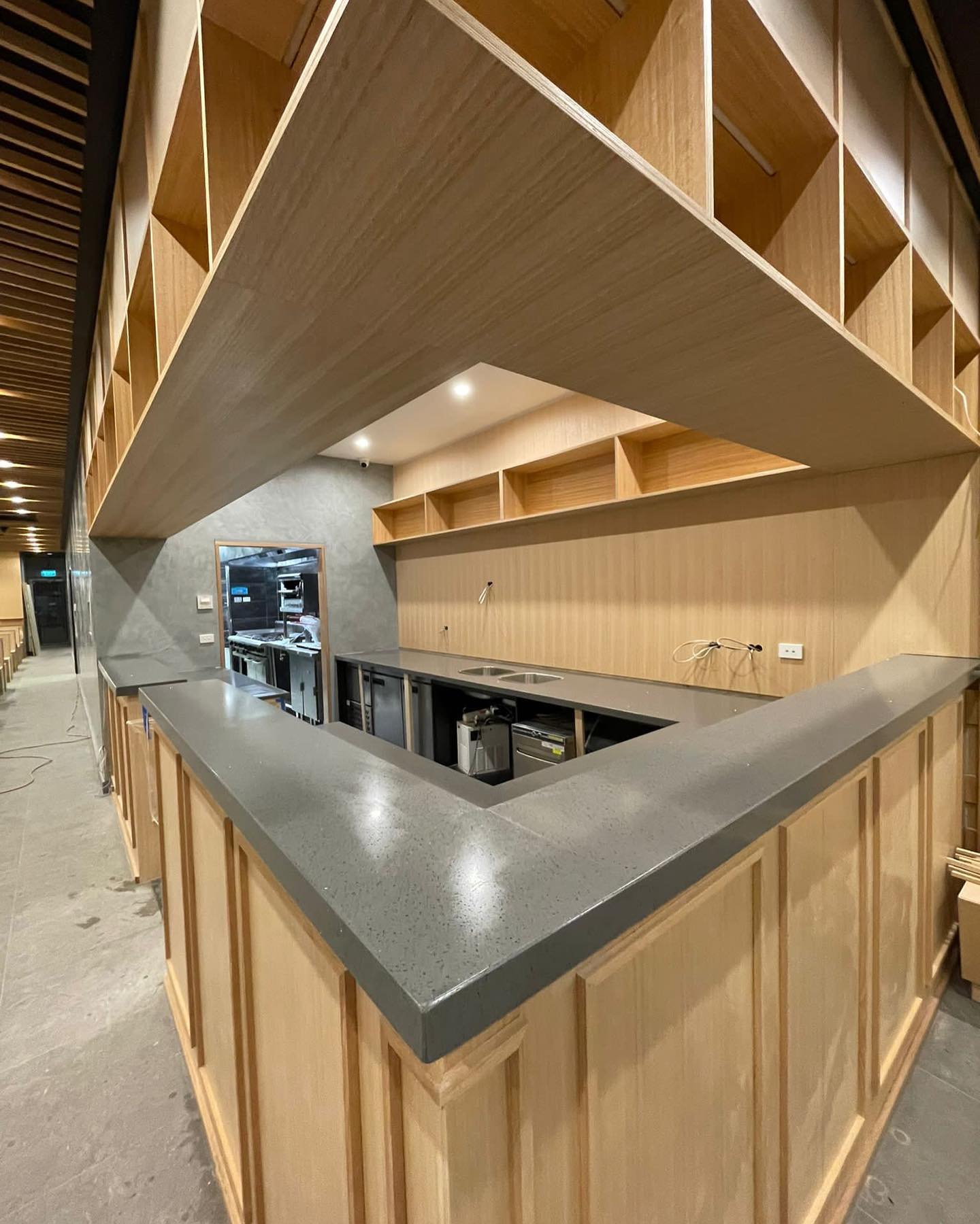 Full-height view of a grey stone L-shaped counter under open timber shelving