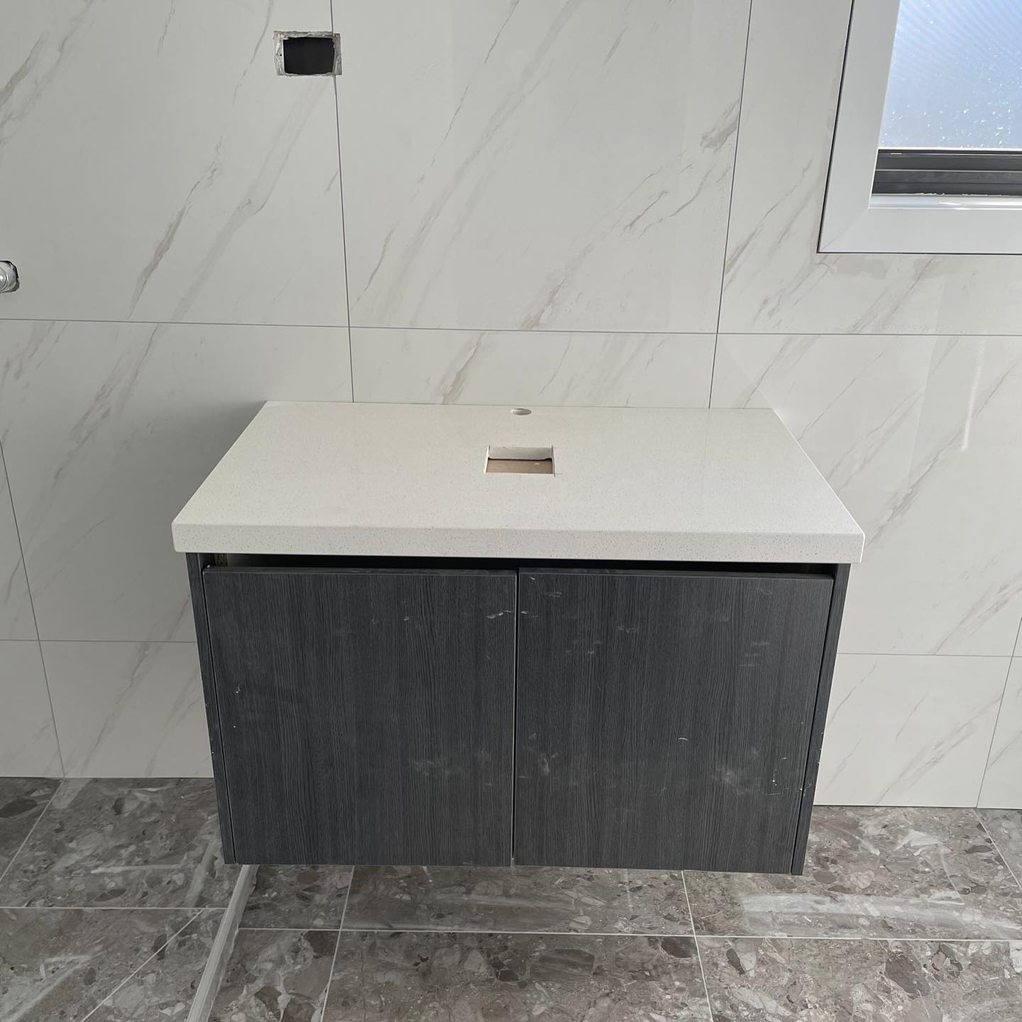 Wall-hung vanity with a white stone top and dark cabinet