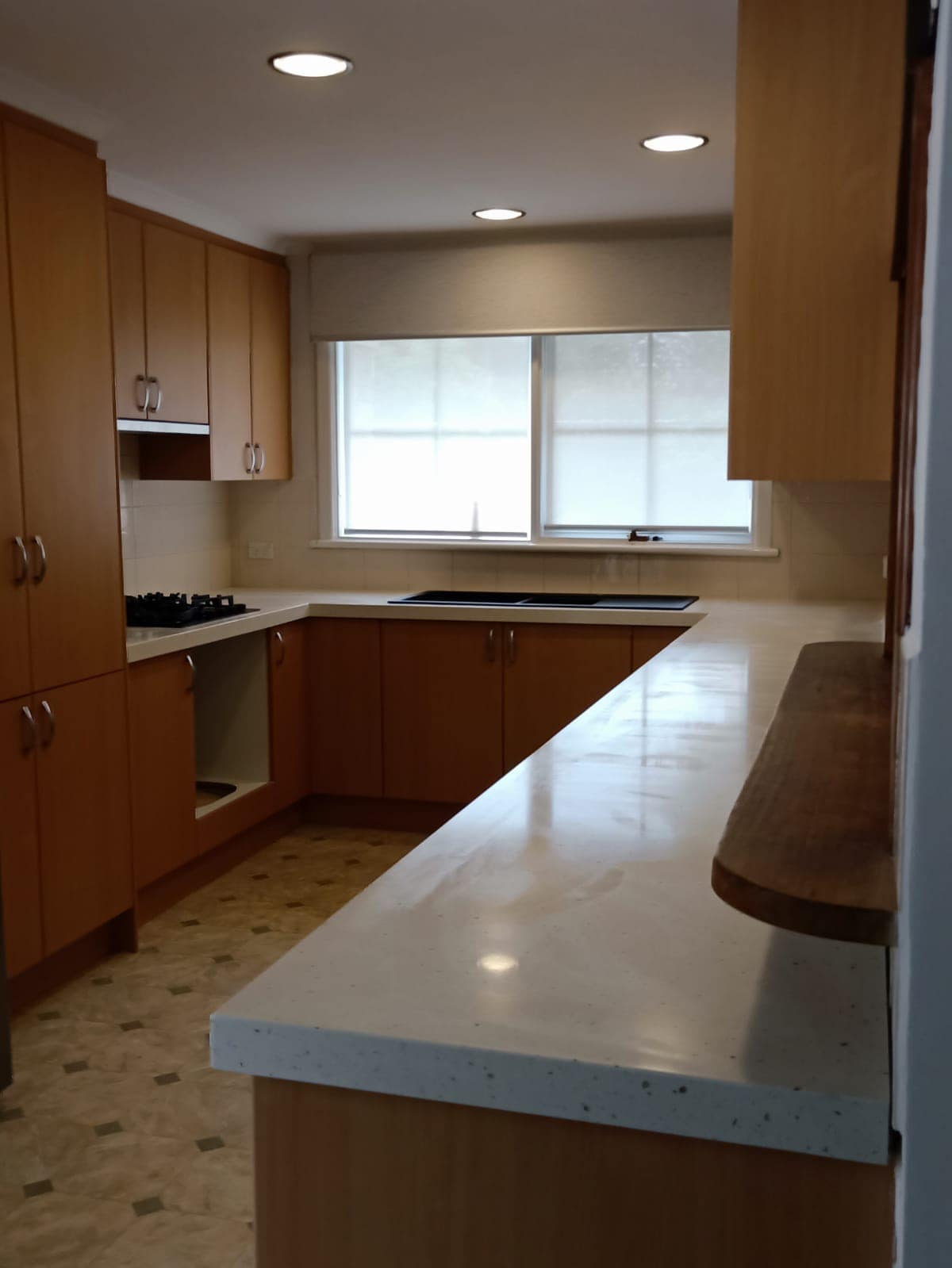 The same timber kitchen with a pale grey stone benchtop