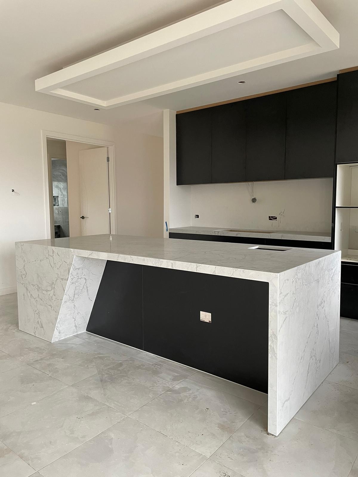 Marble-look waterfall island with a black panel front, seen from the side