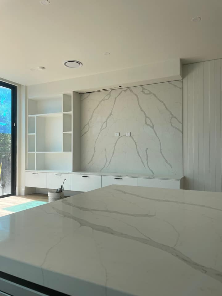 White stone benchtop with grey veining and a matching stone feature wall