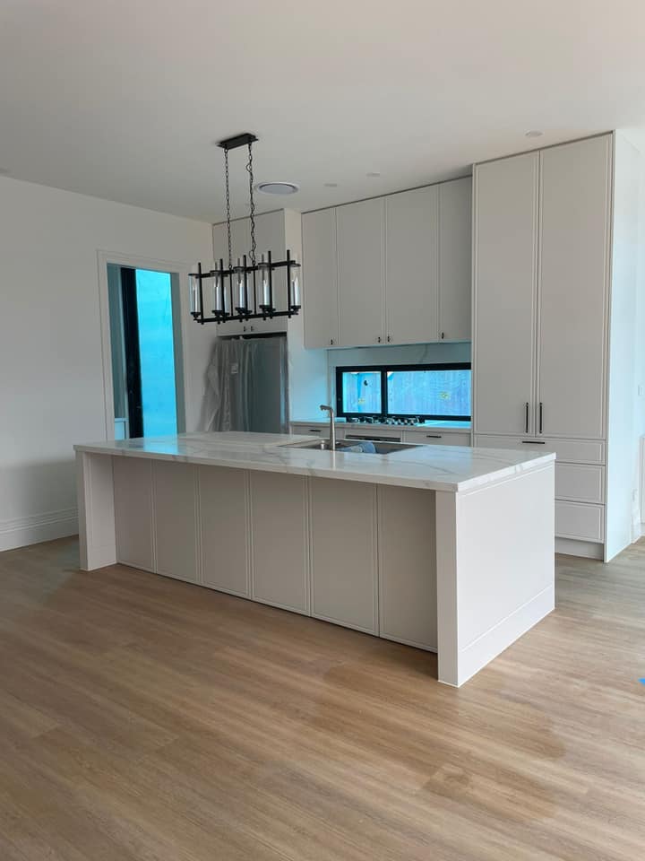Kitchen island with a white stone top and waterfall ends on a timber floor