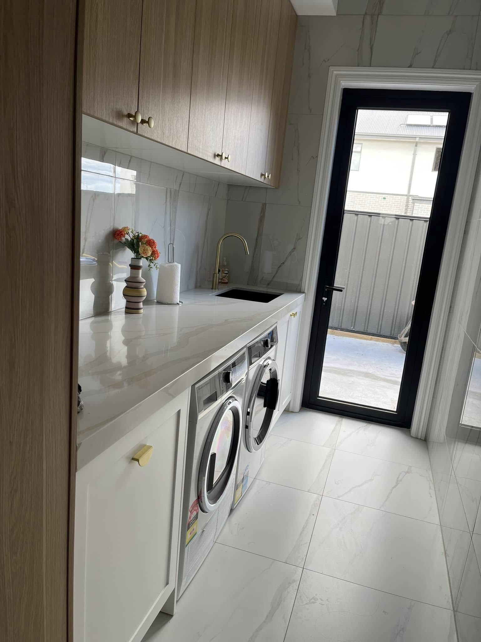 Laundry with a white marble-look benchtop above a washer and dryer