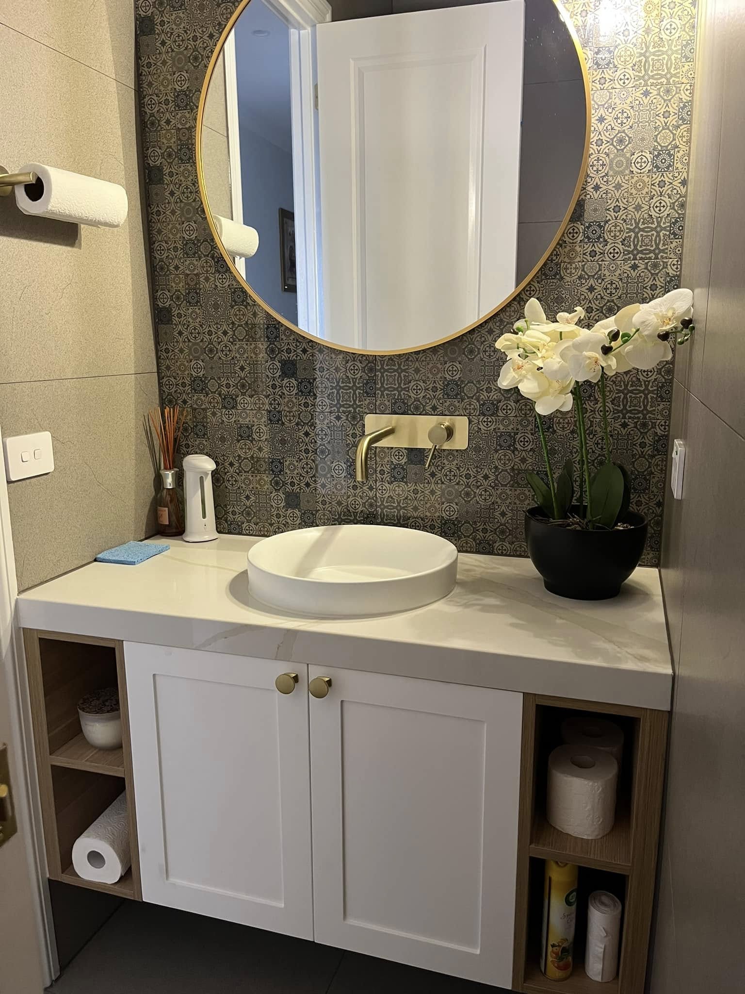 Bathroom vanity with a stone top and round white basin under a round mirror