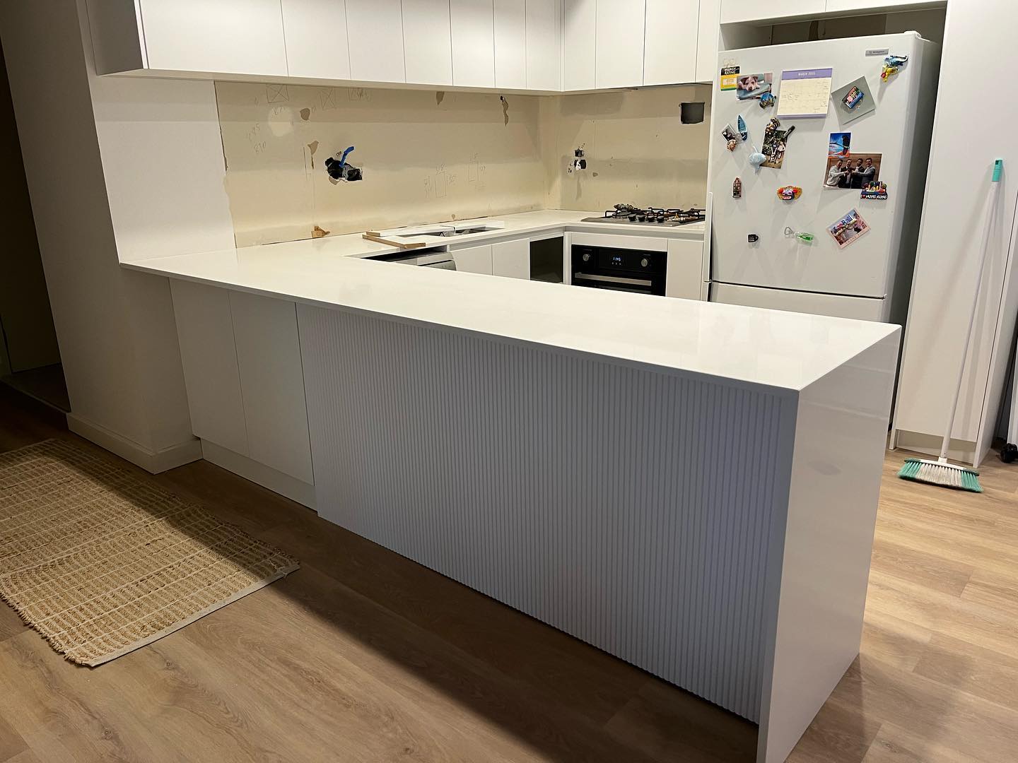 White stone peninsula benchtop with a waterfall end and fluted panel