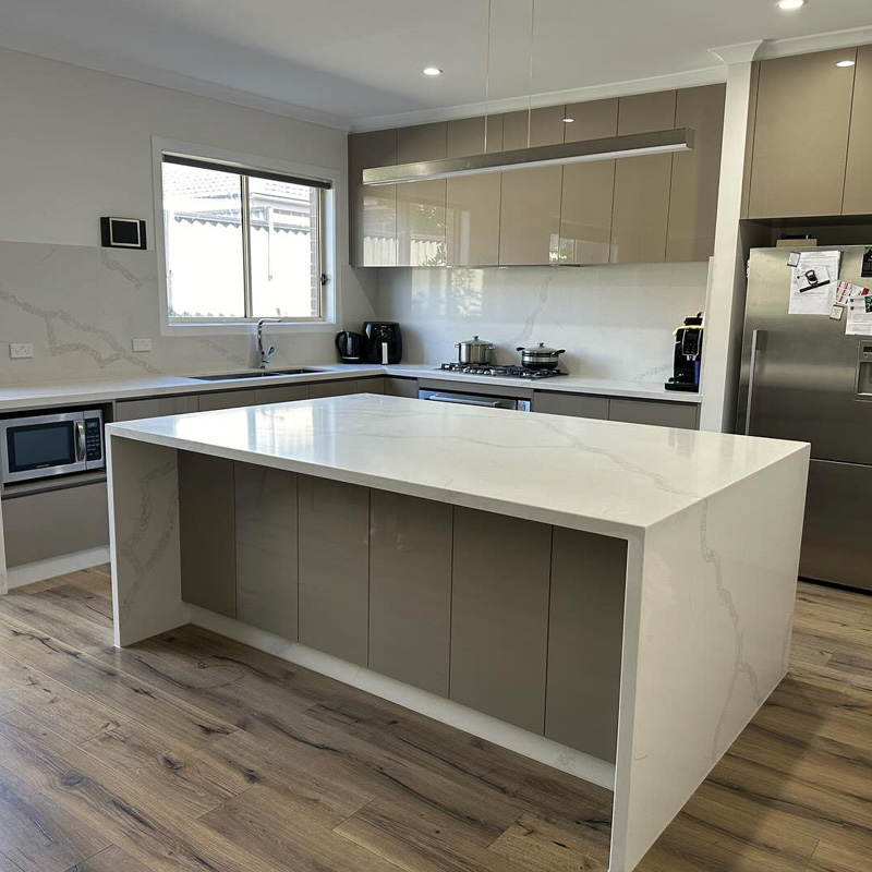 Kitchen island with a white veined stone waterfall benchtop on a timber floor