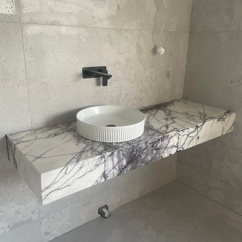 Floating vanity in purple-veined marble with a round white basin