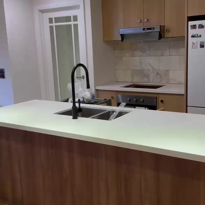 Kitchen bench with a pale stone top, double sink and black tap