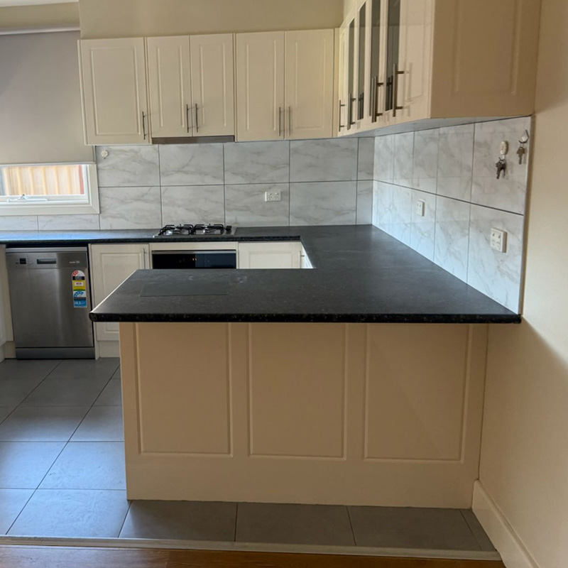 Before: kitchen with a dark speckled benchtop and tiled splashback