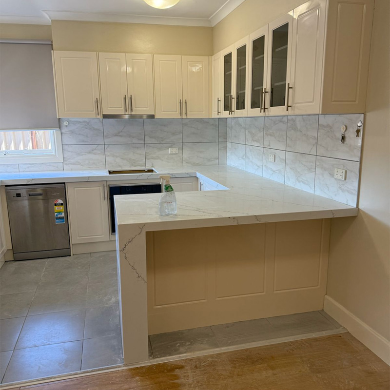 After: the same kitchen with a white marble-look stone benchtop and waterfall end